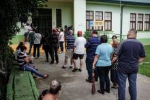 Fotografía de personas haciendo fila para entrar a una institución educativa.