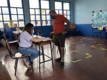 Una persona de pied en frente de otra sentada en una silla, conversando por un trámite.