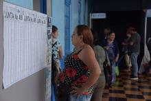 Fotografía de una mujer revisando la información de votación en un centro de votación.
